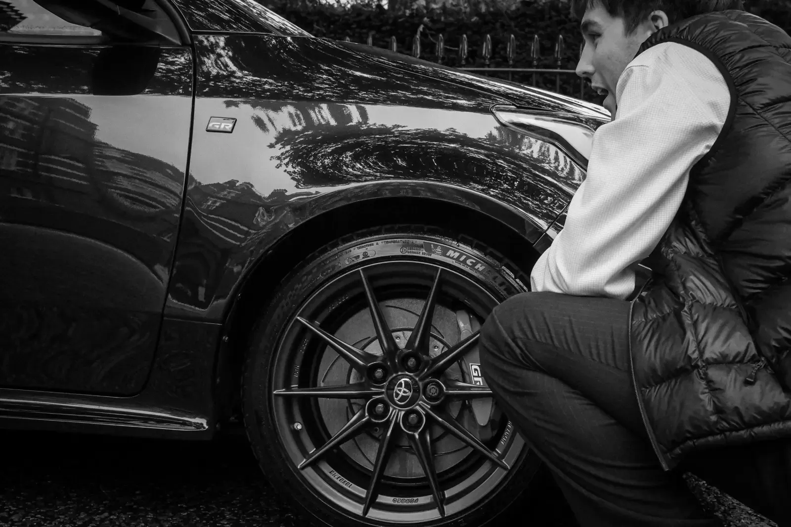 A Kensington and Chelsea Valet customer crouching to admire the wheel of a freshly detailed black car